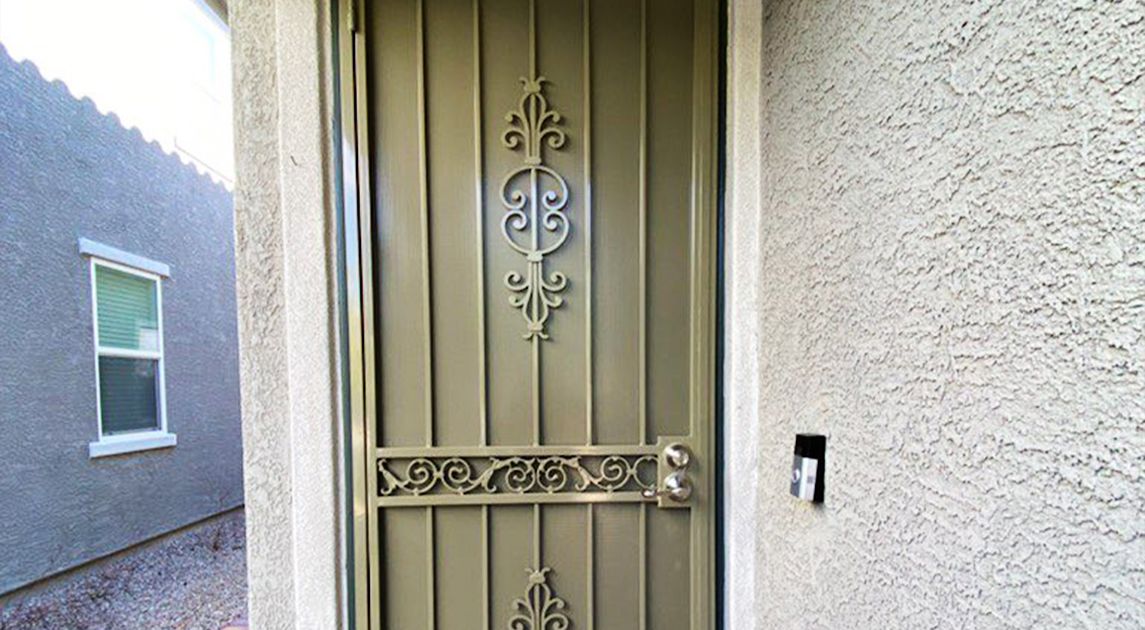 A wrought iron front door with ornate scrollwork and neutral coloring.